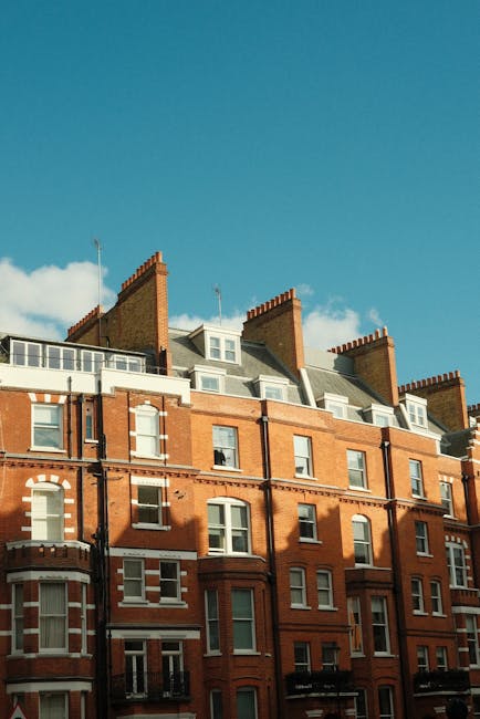 The image depicts the upper floors of a traditional red brick residential building with white window frames and decorative details. The building features multiple bay windows, some with small balconie